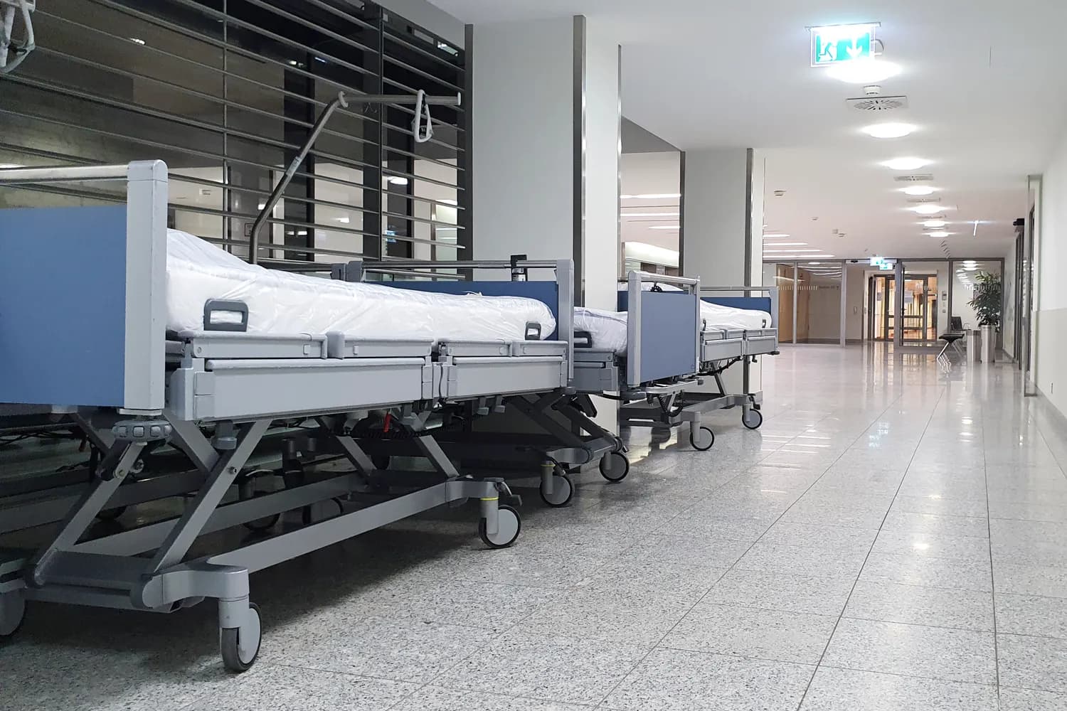 A bright hospital corridor lined with beds under even lighting