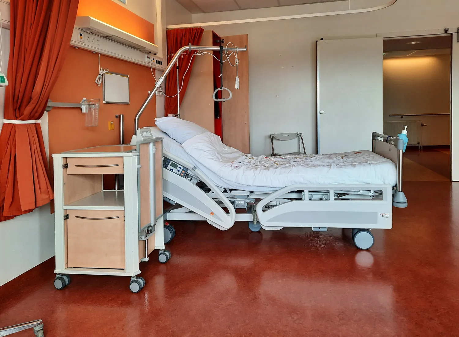 A clean, modern hospital patient room with an adjustable bed
